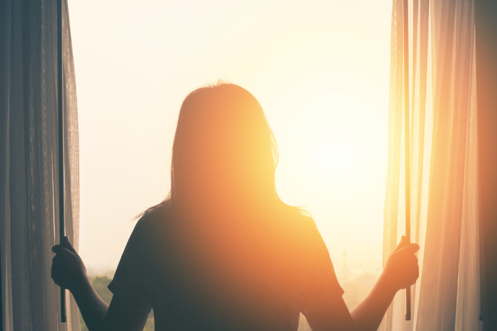 Frau abends am offenen Fenster