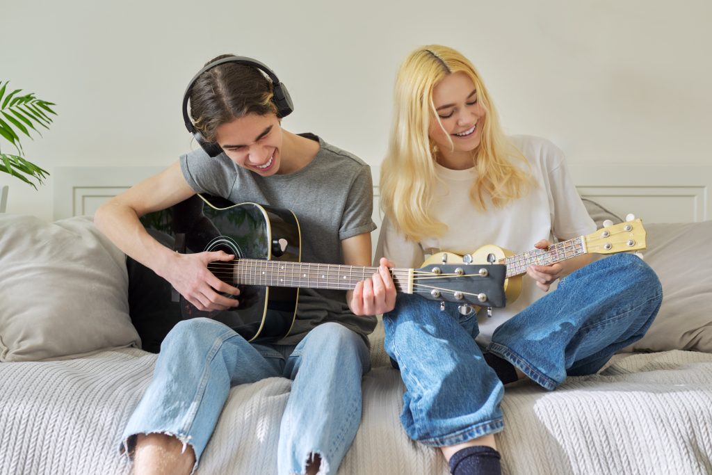Teenager spielen Gitarre auf dem Bett