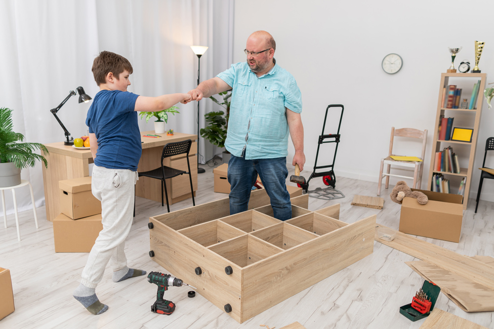 Vater und Sohn bauen neuen Möbel für das Jugendzimmer auf.