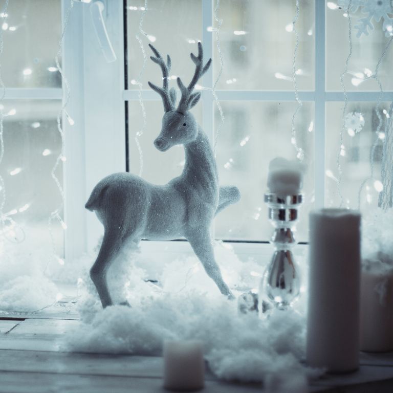 Winterliche Fensterdeko mit weißem Hirsch und weißer Kerze